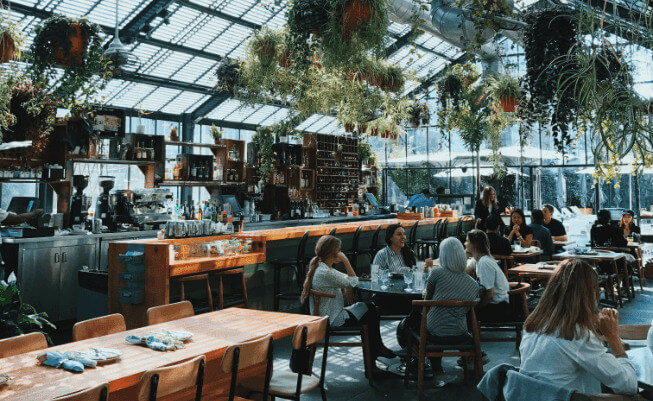 Dining inside a large restaurant with glass ceiling and an abundance of plants