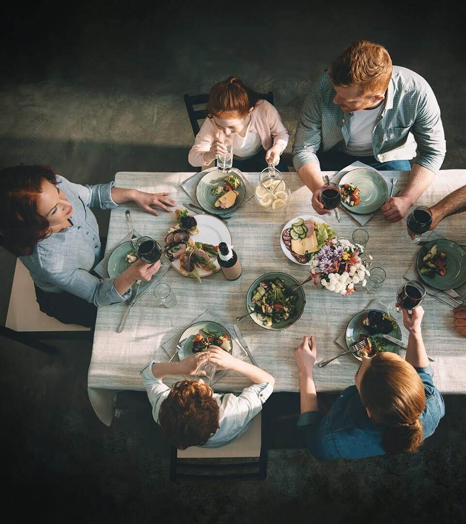 A family of six eating and talking while sitting around a dinner table